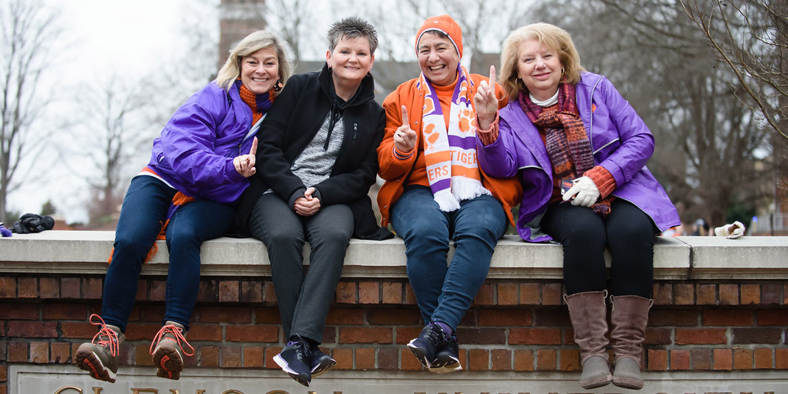 Clemson fans sitting on wall at Clemson University.